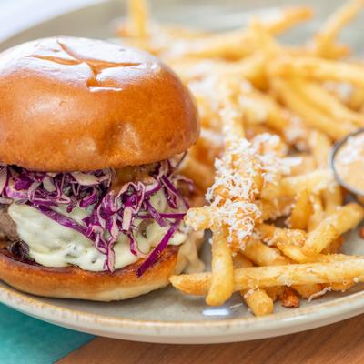 Prime burger served with fries on a stoneware plate.
