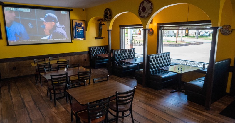 Cozy interior dining area with wooden tables and chairs, and upholstered booths along windows