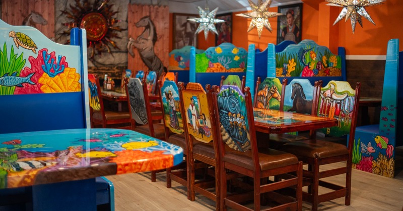 A restaurant interior with colorful, painted tables and chairs