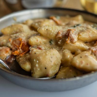 Bowl of creamy pancetta gnocchi, close-up.