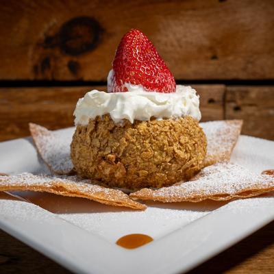Fried ice cream topped with whipped cream and a strawberry.