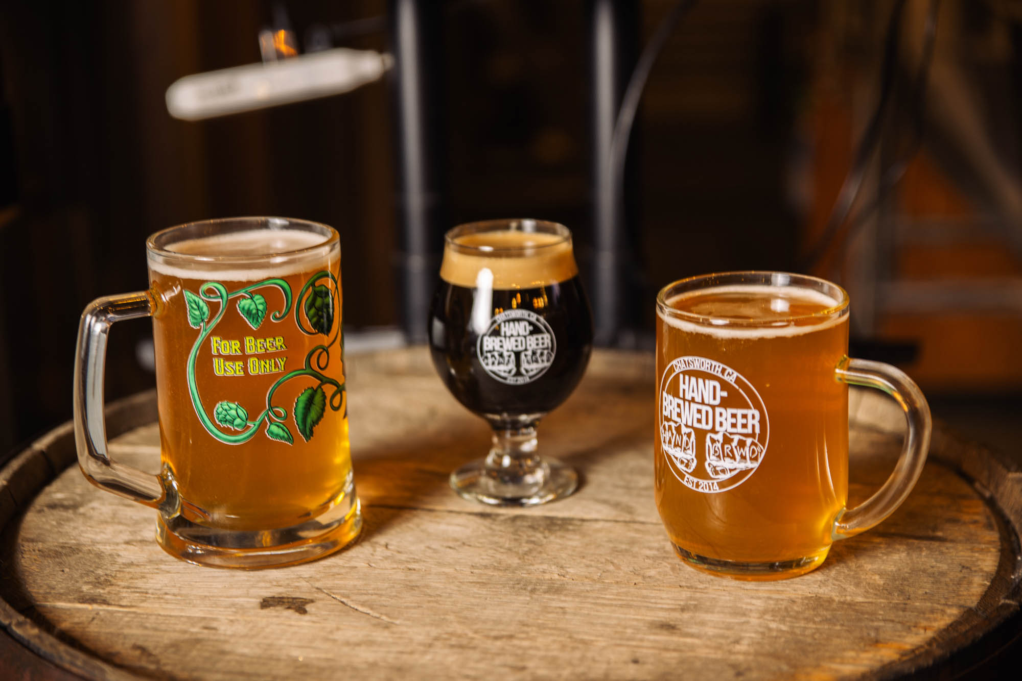 3 glasses of beer atop a barrel