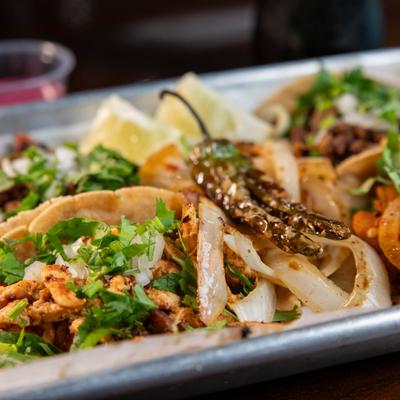 Platter of street tacos served with grilled onions, lemon wedges and jalapeno.