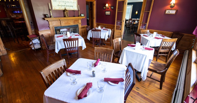 Interior, white cloth tables for four, wooden flooring, vintage fireplace