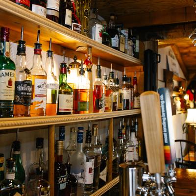 Pub details, shelves of various liquor bottles, glasses hang overhead, beer taps.