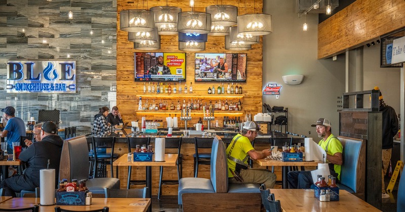 Interior, tables and blue leather high back benches, bar in the back