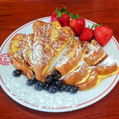 French toast dusted with powdered sugar, accompanied by fresh blueberries and strawberries.