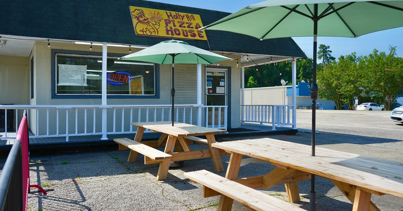 Outdoor seating area, with conjoined tables and benches, and parasols