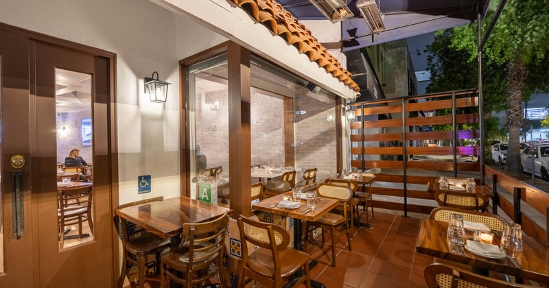 Outside, patio with wooden tables, cane chairs, terracotta roof tiles, overhead heaters