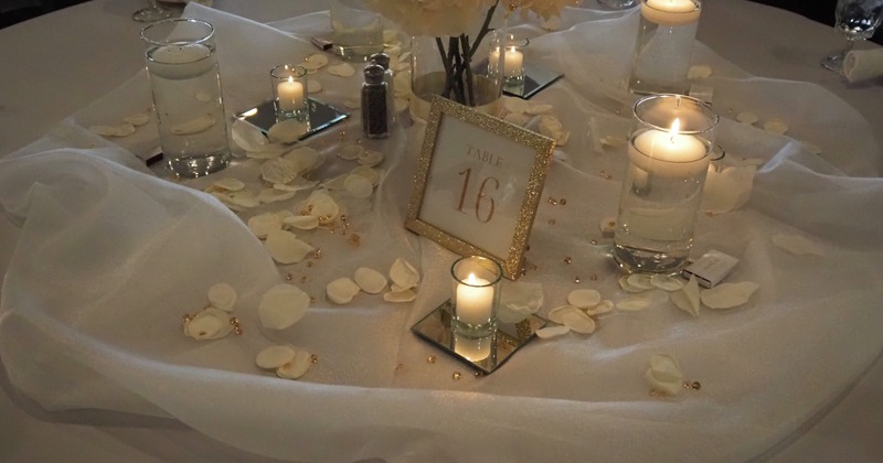 Gold framed table number, candles and flower petals
