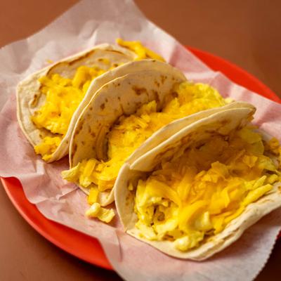 Breakfast tacos filled with scrambled eggs and melted cheese on flour tortillas.