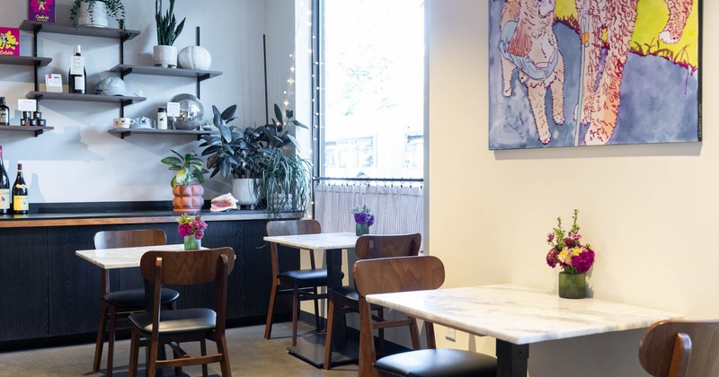 Bright  interior - plants, wall shelves, marble tables, wooden chairs and colorful artwork