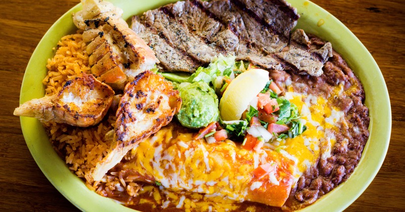 Shellfish tails, steak, and enchilada served with rice and beans