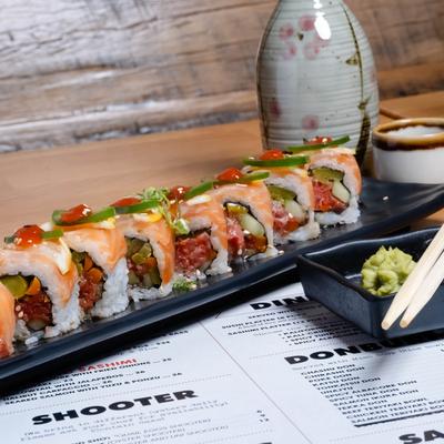 The Too Damn Long roll served on a table, chopsticks rest beside wasabi and ginger.