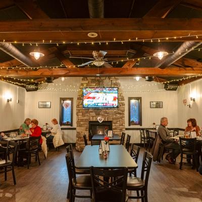 Dinig room featuring a stone fireplace, tables with chairs and string lighting.