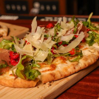 Flatbread with mozzarella, prosciutto, olives, red peppers, arugula, and parmesan.