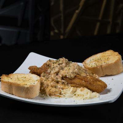 Fried fish with creamy sauce, spaghetti, and garlic bread.
