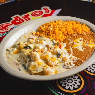 Seafood enchiladas served with rice and refried beans.