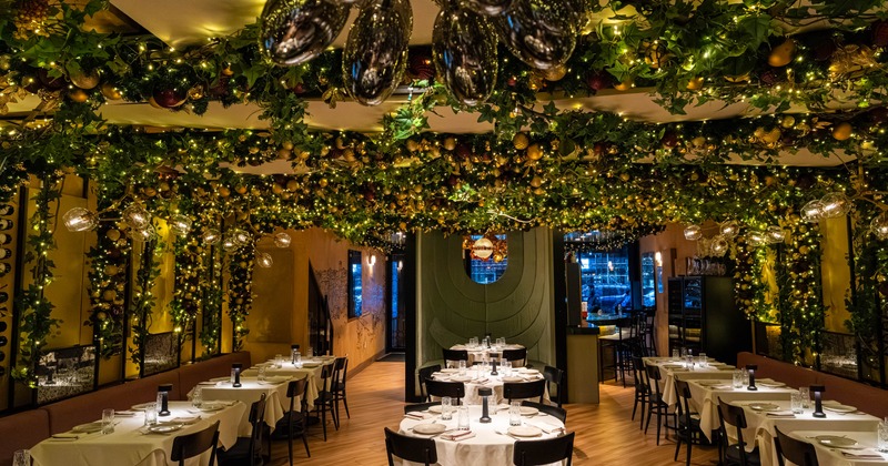 Open space dining room with round tables, banquette benches and tables, lavishly decorated ceiling