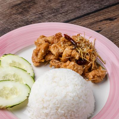 Lemongrass fried chicken served with white rice and cucumber slices on pink plate.