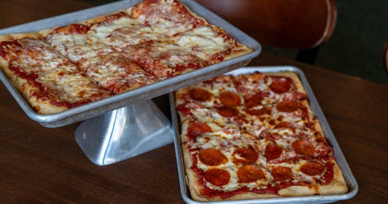 Two rectangular pizzas, one cheese and one pepperoni, served on metal pans