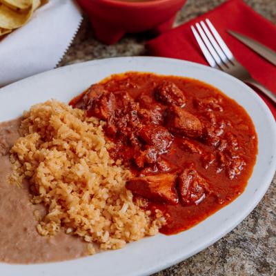 Asado de Puerco served with sides of rice and refried beans.