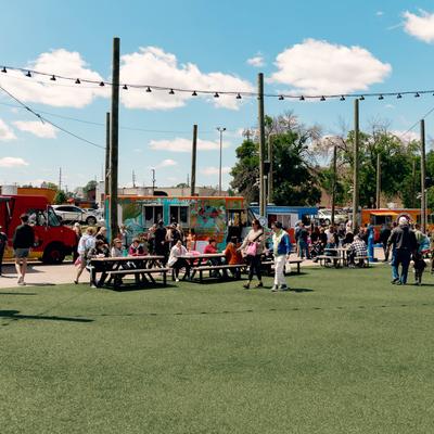 A large grass field, people at tables, the food truck.