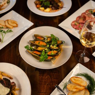 Multiple food plates and glasses of wine displayed on table.