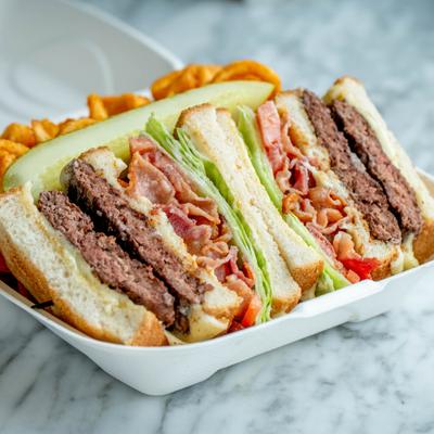 Cheeseburger club sandwich served with curly fries and a pickle.