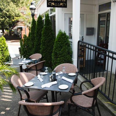 Outdoor dining area with set tables, surrounded by shrubs.