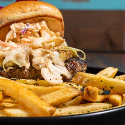 Burger with coleslaw and seasoned fries.