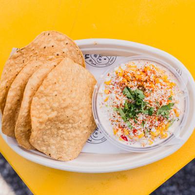 Queso fundido garnished with spices and cilantro and served with fried tortillas.