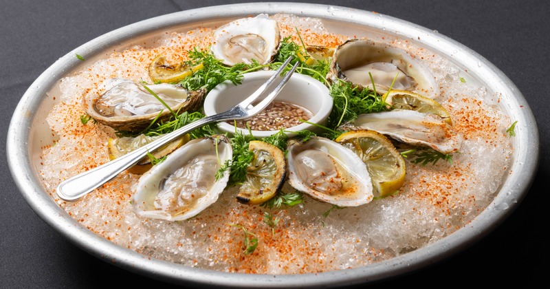 Oysters on ice with lemon slices and herbs
