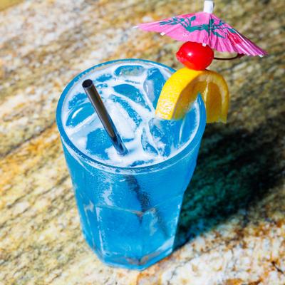 Blue Hawaiian cocktail with cherry, lemon, and umbrella garnishes.