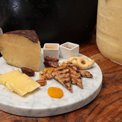 A board with cheese, sweet focaccia bread, dried fruit, and condiments