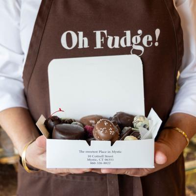 A person is holding a box of assorted chocolates.