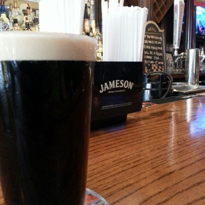 A pint of dark beer on the bar counter.