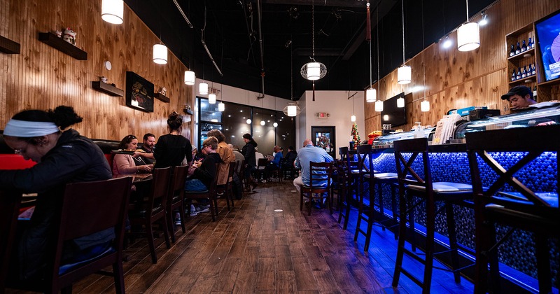 Interior, sushi bar, and dining area with guests enjoying their food