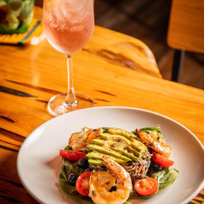 Salad of avocado, wild rice and shrimp, accompanied by a glass of cocktail