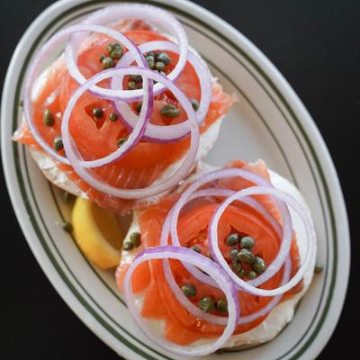 Smoked salmon and cream cheese bagel sandwich with capers and red onion.