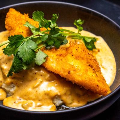 Bowl of fried Fish and Grith, garnished with fresh herbs.