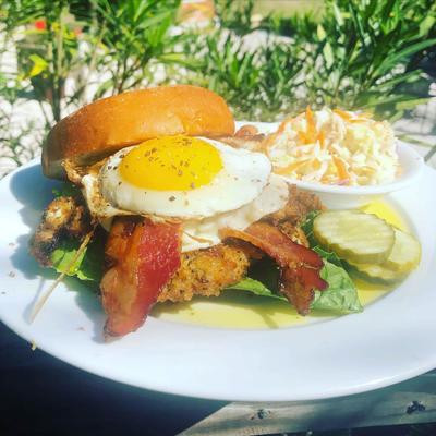 Chicken schnitzel sandwich with bacon, provolone, Romaine lettuce, and topped with an egg.
