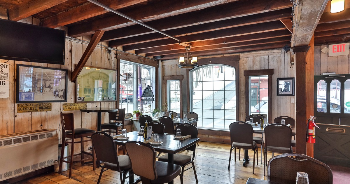 Interior, dining area, wood panel walls, exposed beams, tables, chairs, large windows and wall decor