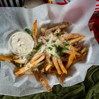Parmesan Truffle Fries in a paper-lined basket with a side of dipping sauce.