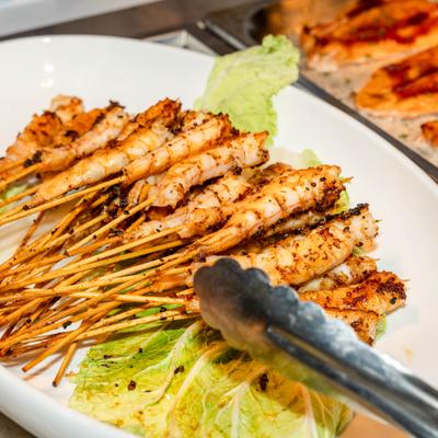 Chicken satay skewers served on a platter over lettuce.