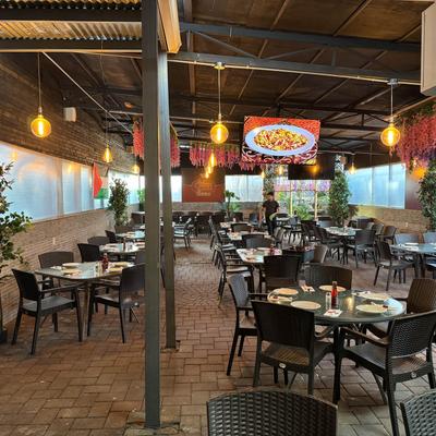 Patio dining  under a covered structure with string lights and floral decorations.