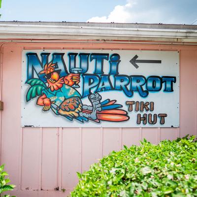 Nauti Parrot Tiki Hut sign with a cartoon parrot holding a cocktail.