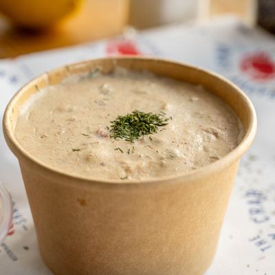 Salmon Chowder served in a takeout container, garnished with dried herbs.