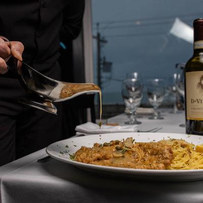 A hand pouring sauce on a meal.