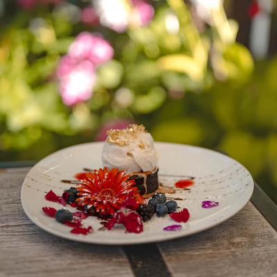 Dark Chocolate Cake topped with ice cream, garnished with berries and flowers.